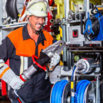 Fire fighter wearing helmet and uniform checking hydraulic cutter at fire engine